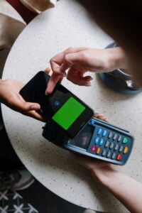 A close-up of a smartphone making a contactless payment on a terminal in a cafe setting.