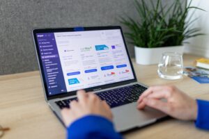 Close-up of hands on a laptop browsing an e-commerce site in a modern office.